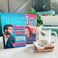 Photo of two books by Meghan Quinn, "Those Three Little Words" and "Kiss and Don't Tell" and a glass mug for the Vancouver Agitators hockey team 